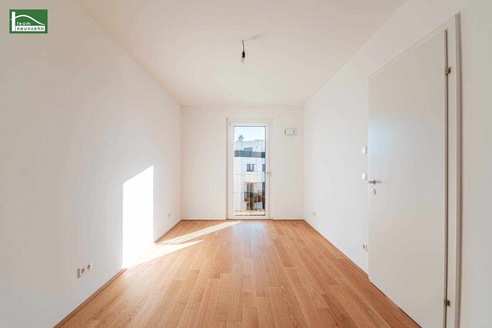 Helles Zimmer mit Holzboden und Zugang zu einem kleinen Balkon, ideal als Schlaf- oder Arbeitszimmer.