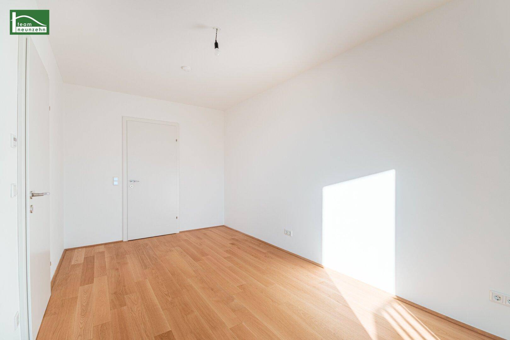 Leeres Schlafzimmer mit Holzboden und weiß gestrichenen Wänden, bereit zur individuellen Gestaltung.