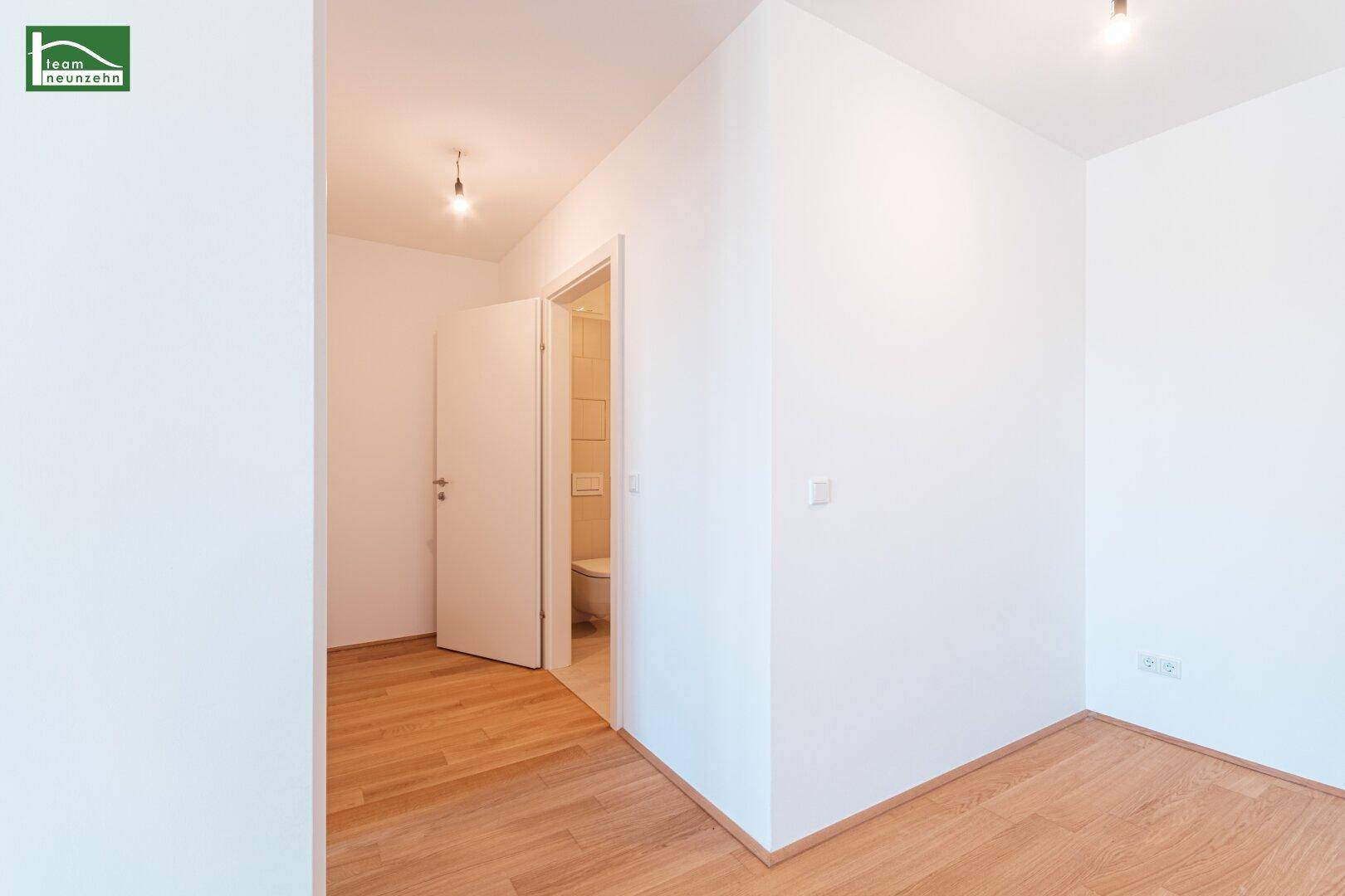 Heller Flur mit Parkettboden und Zugang zu einem Gäste-WC.
