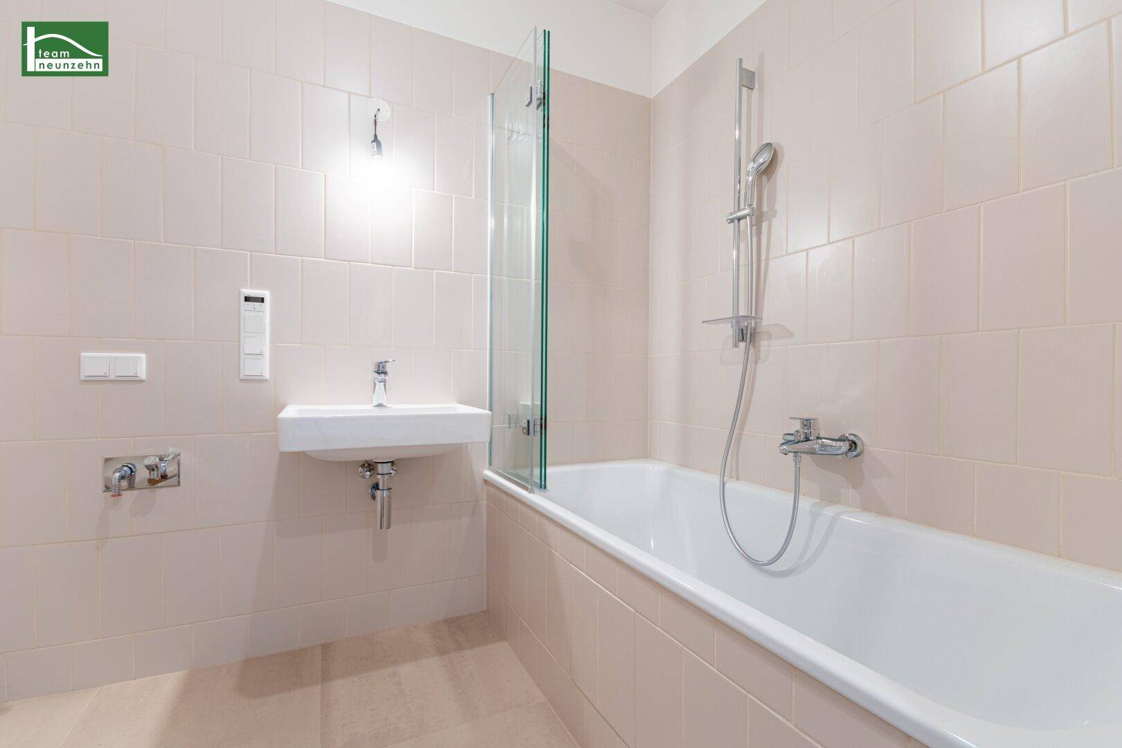 Modernes Badezimmer mit Badewanne, Dusche und hellen Fliesen.