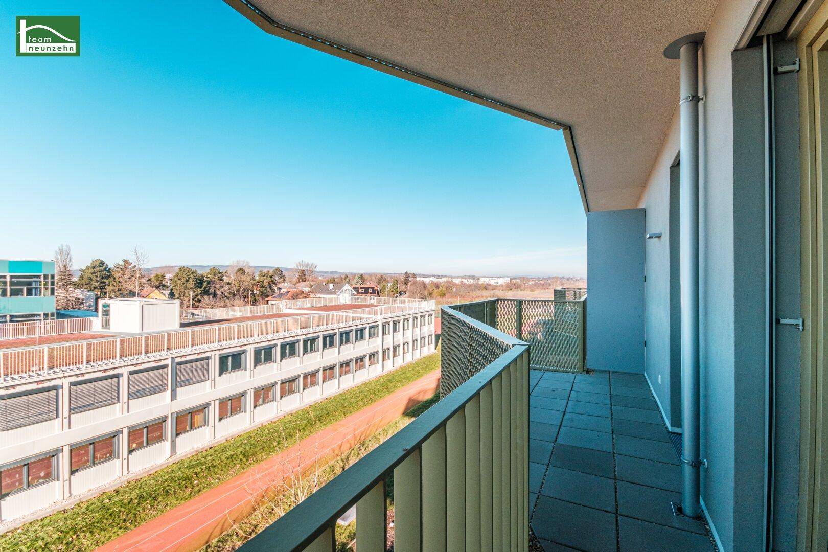 Langer Balkon mit weitem Blick über die umliegende Landschaft und Gebäude.