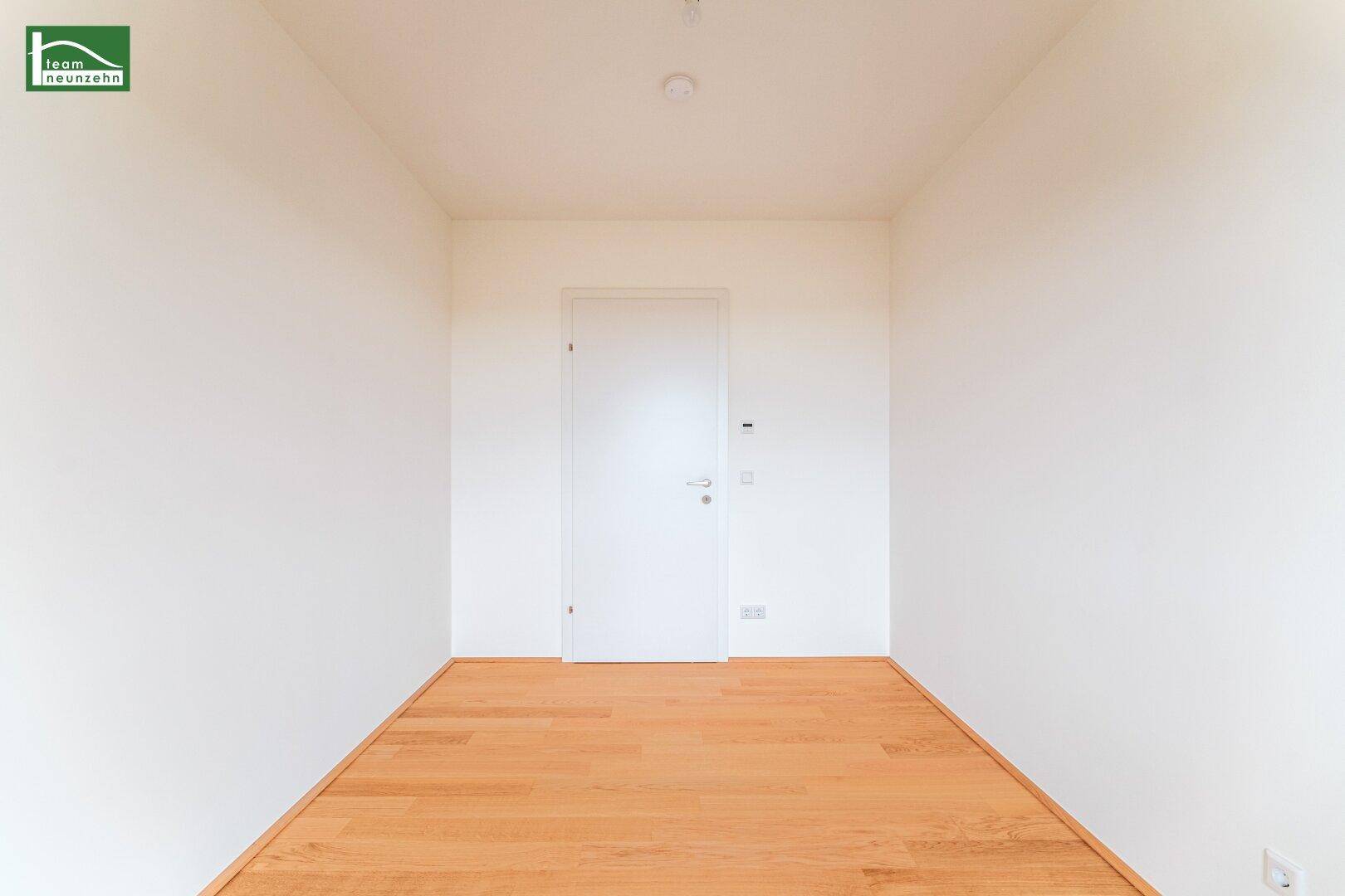 Leerer Raum mit hellem Parkettboden und einer weißen Tür, bereit für individuelle Gestaltung.