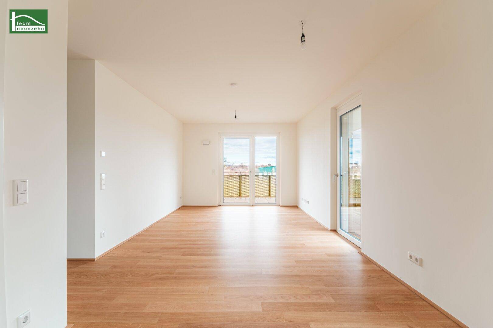 Helles, leeres Zimmer mit Parkettboden und Zugang zu einem Balkon, ideal für Wohn- oder Schlafbereich.