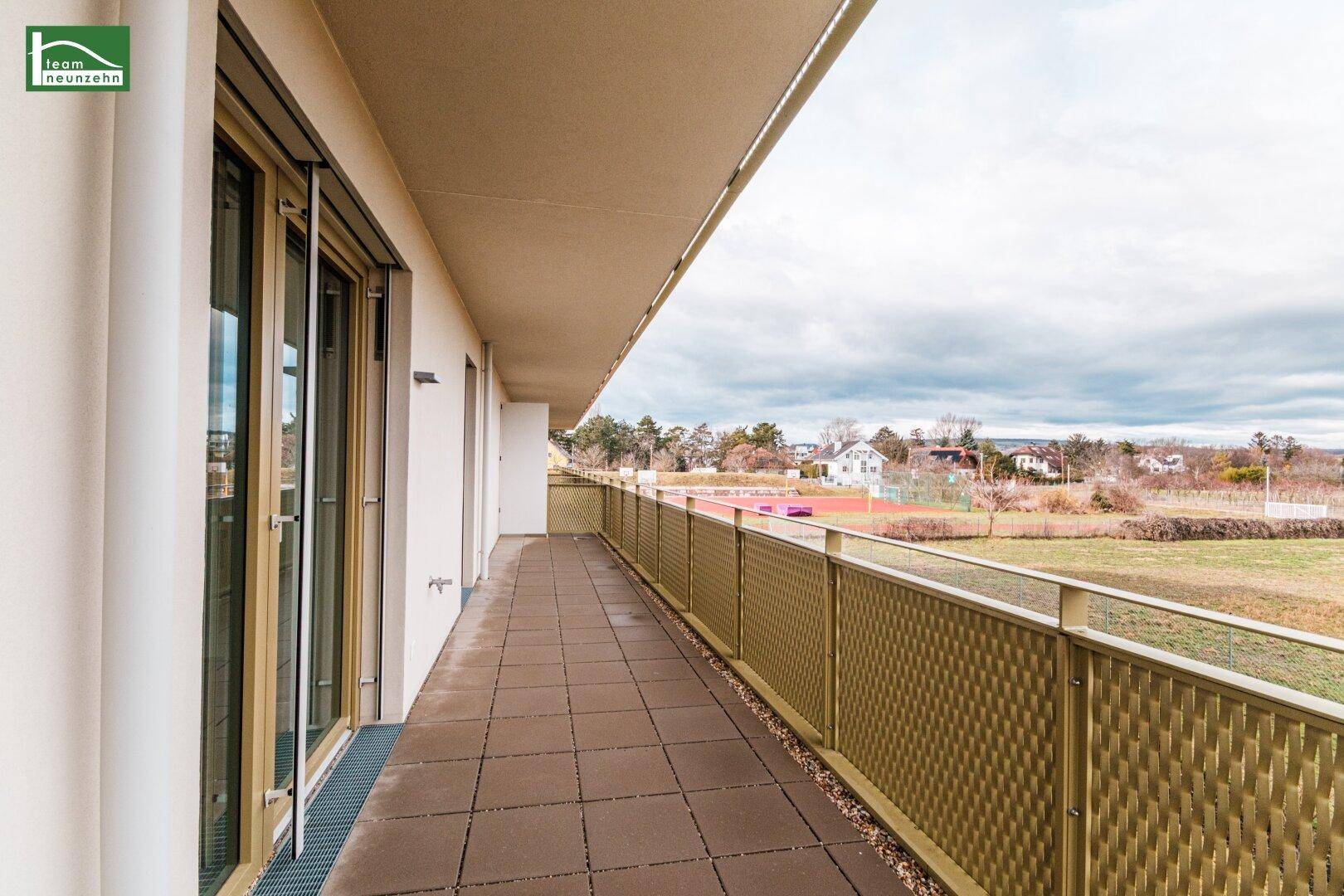 Breiter Balkon mit Fliesenboden und weitem Blick über die umliegende Landschaft und Felder.