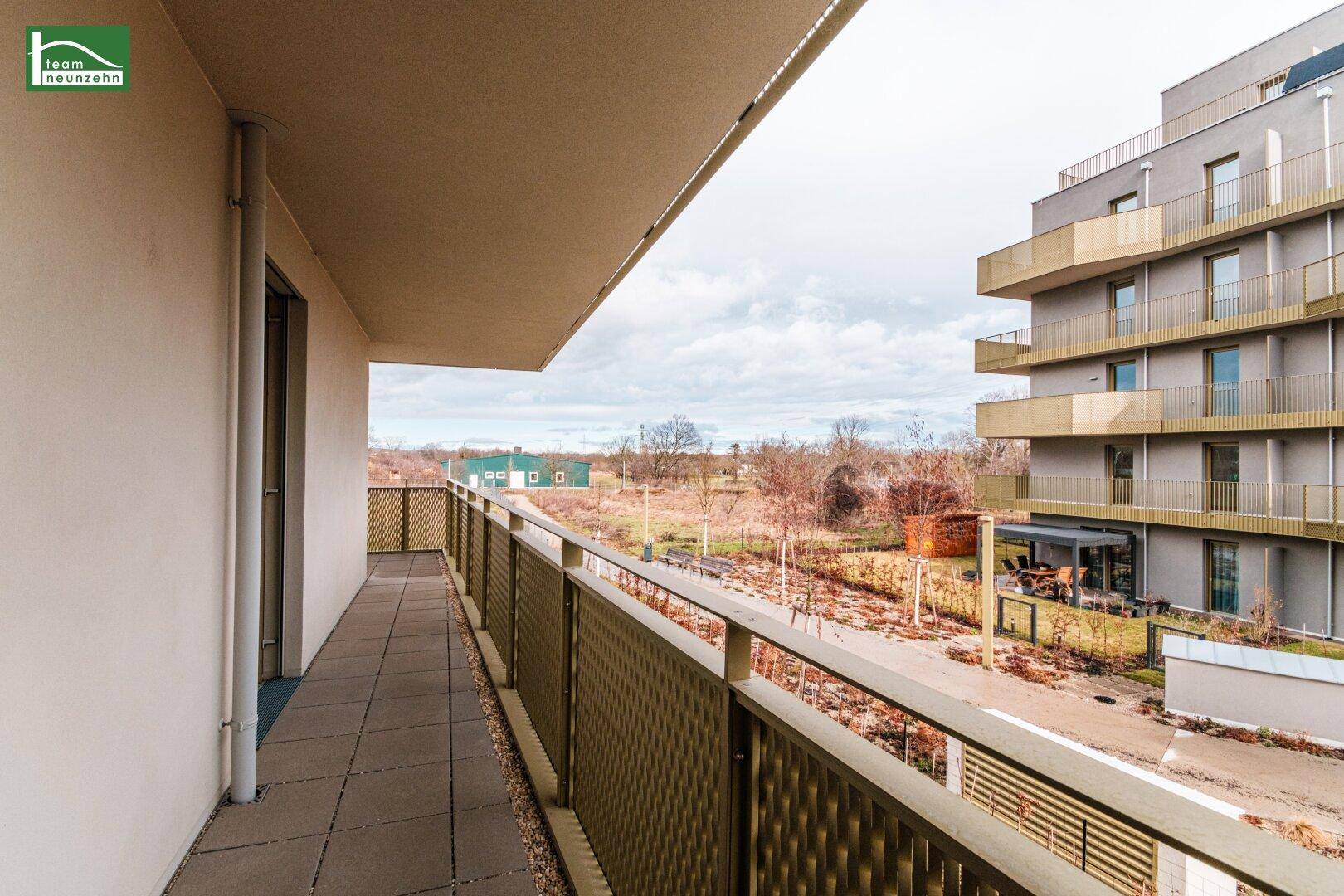 Langer Balkon mit Fliesenboden und Metallgeländer, bietet einen weiten Blick auf die Umgebung.