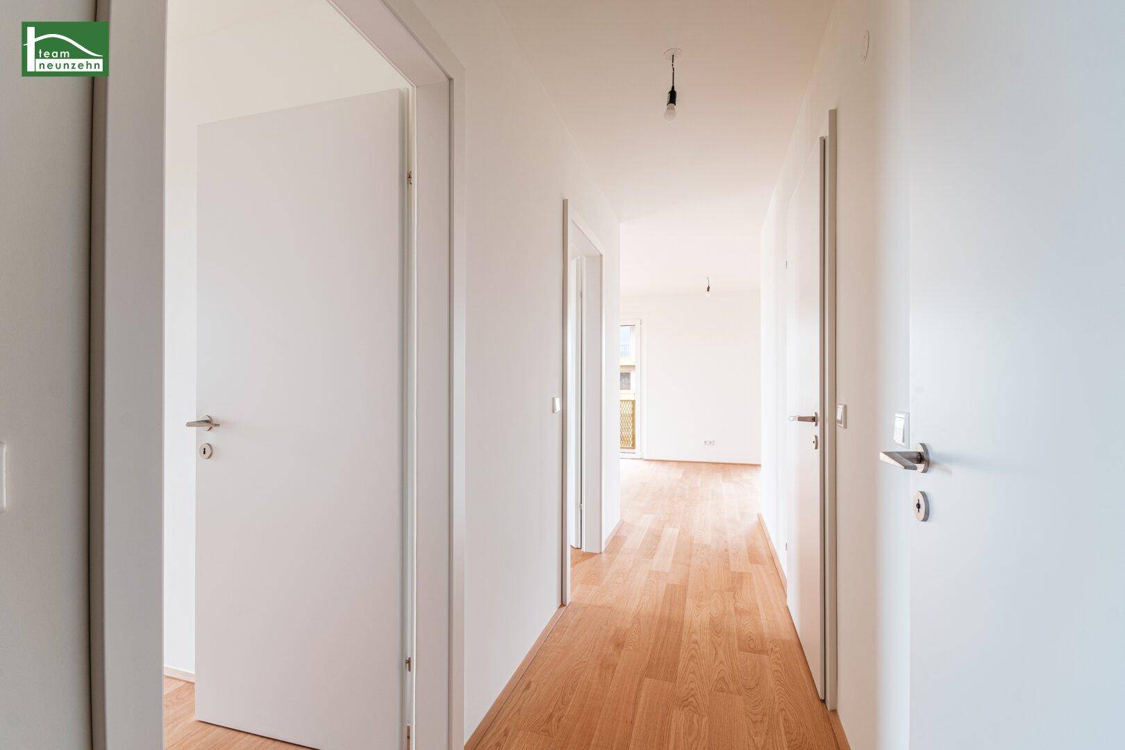 Langer, heller Flur mit Holzboden und mehreren Türen zu den angrenzenden Räumen.