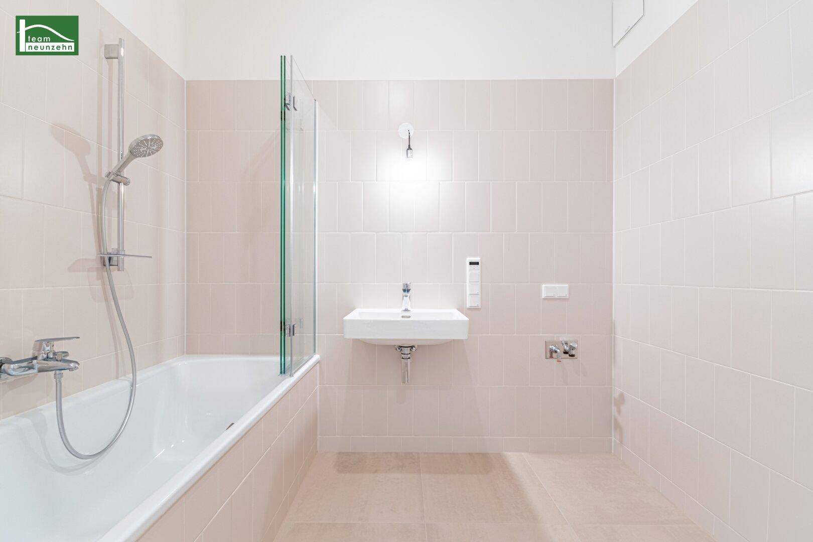 Modernes Badezimmer mit Badewanne, Dusche und hellem Fliesenboden in neutralen Farben.