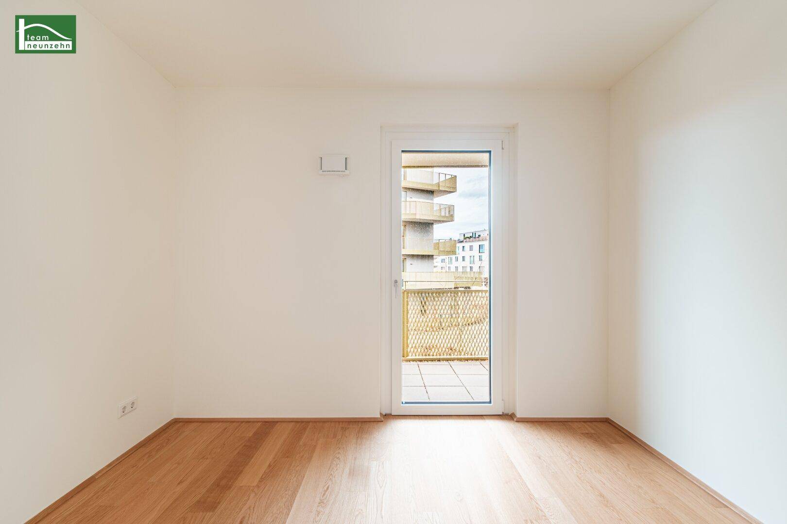Ruhiges Zimmer mit hellem Parkettboden und direktem Zugang zu einem sonnigen Balkon.