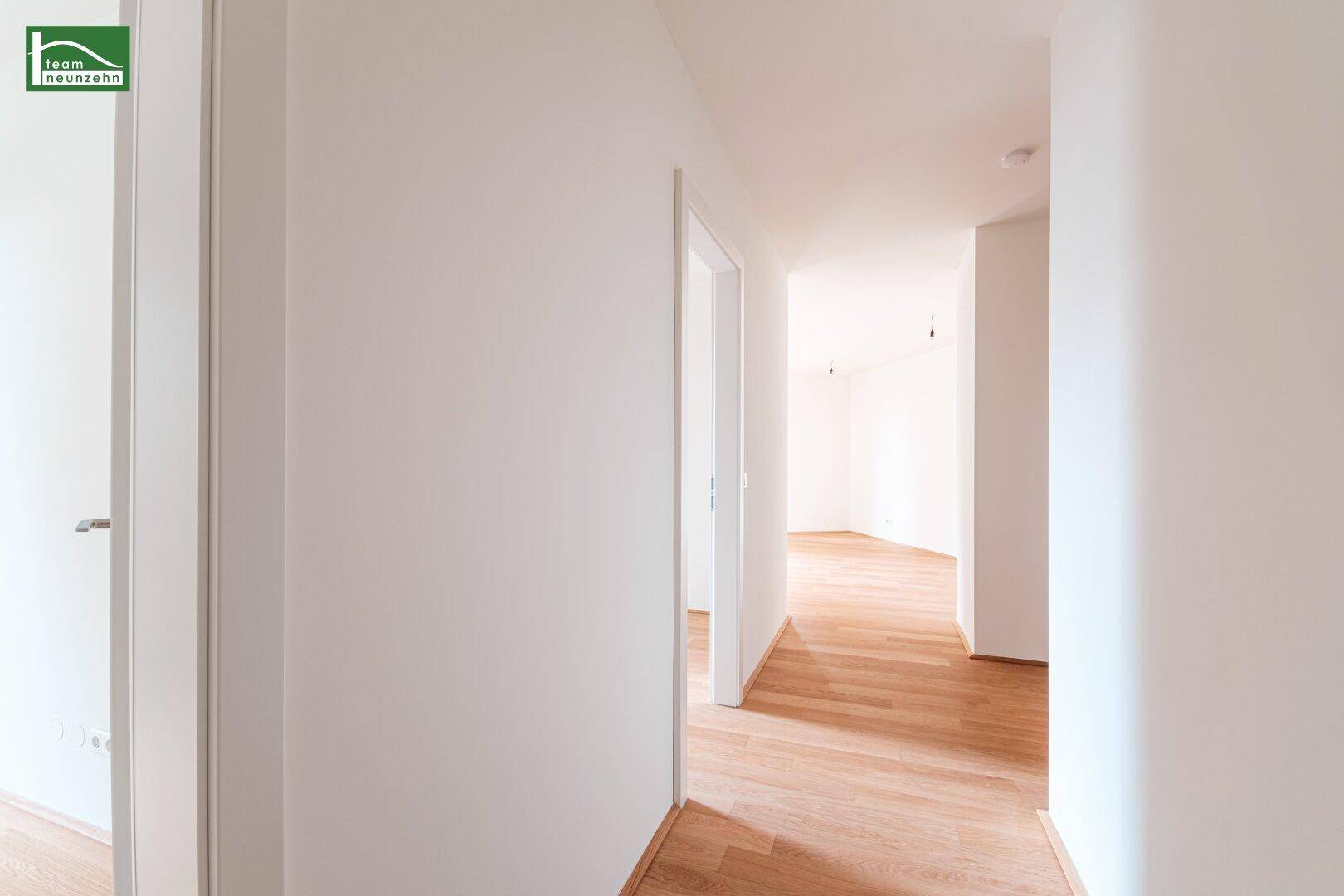 Heller Flur mit Parkettboden, der zu verschiedenen Räumen der Wohnung führt.