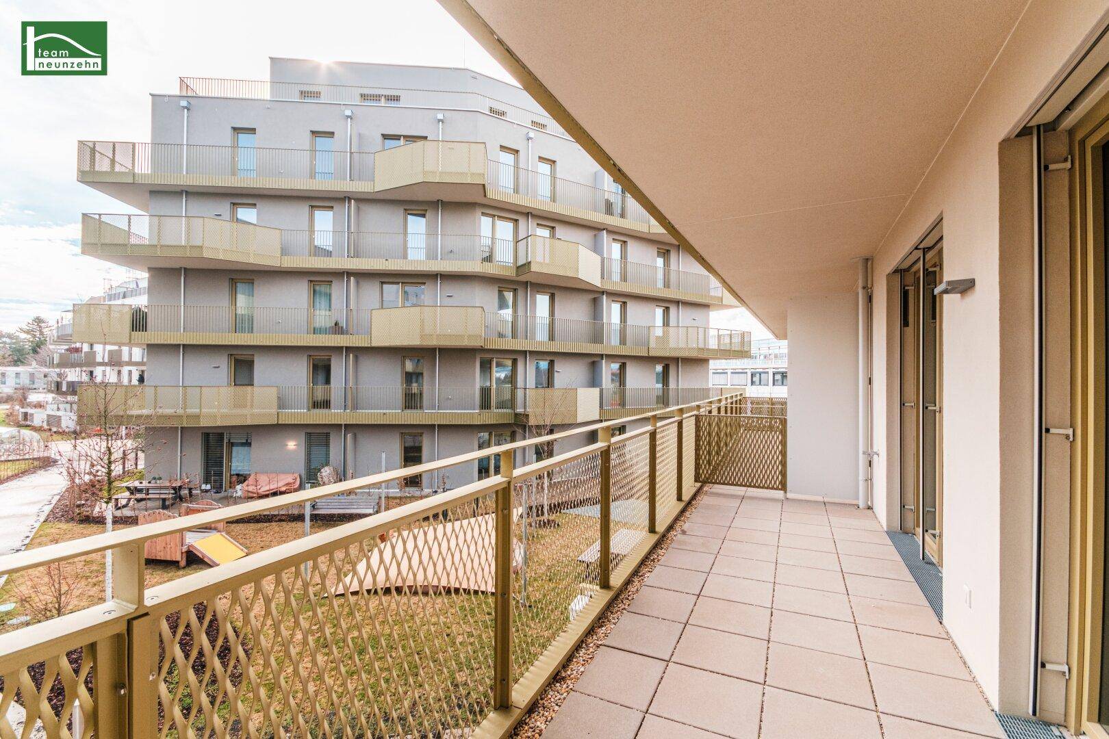Geräumiger Balkon mit Fliesenboden und Blick auf die moderne Wohnanlage.