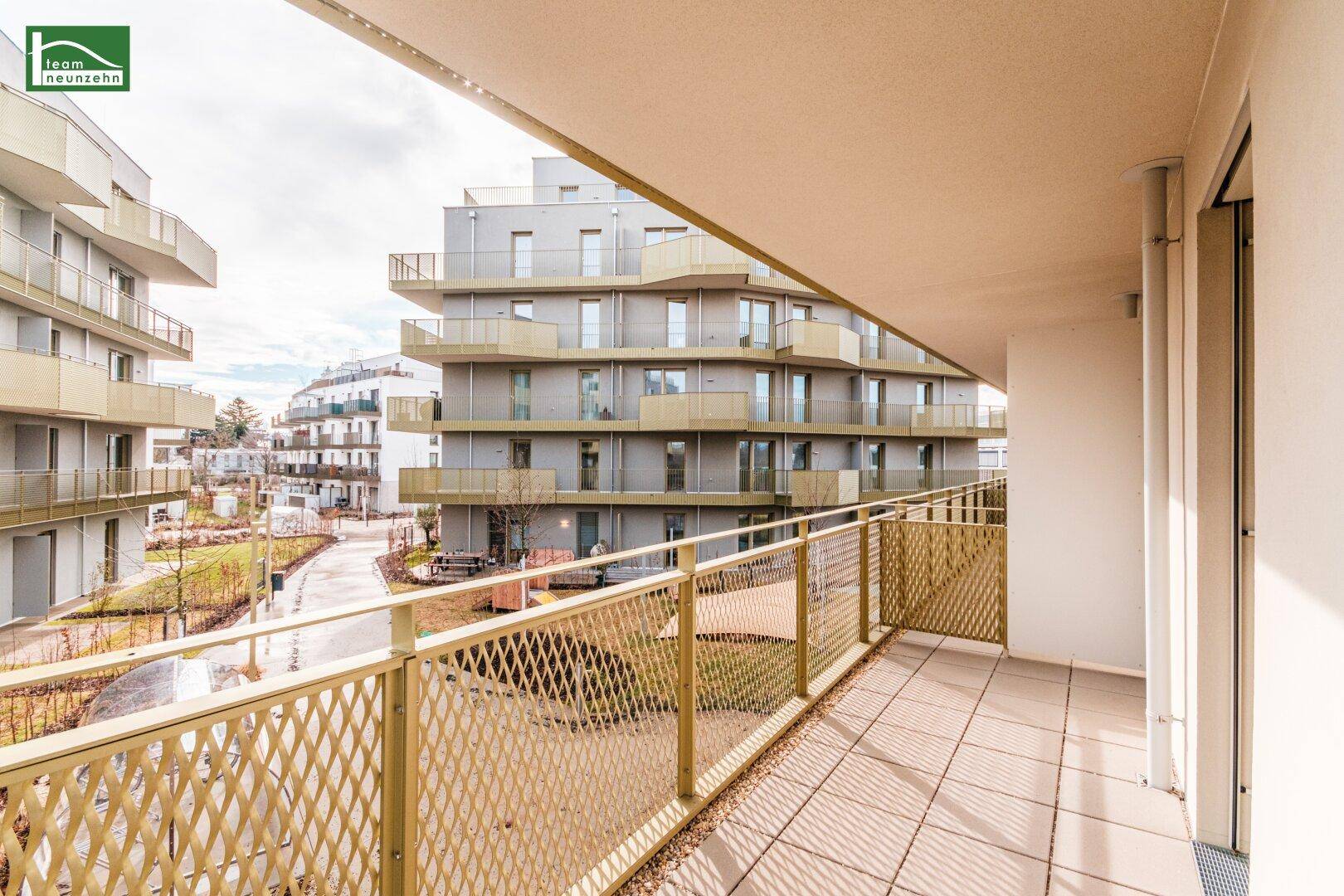 Balkon mit Blick auf die moderne Architektur der umliegenden Wohngebäude und Grünflächen.