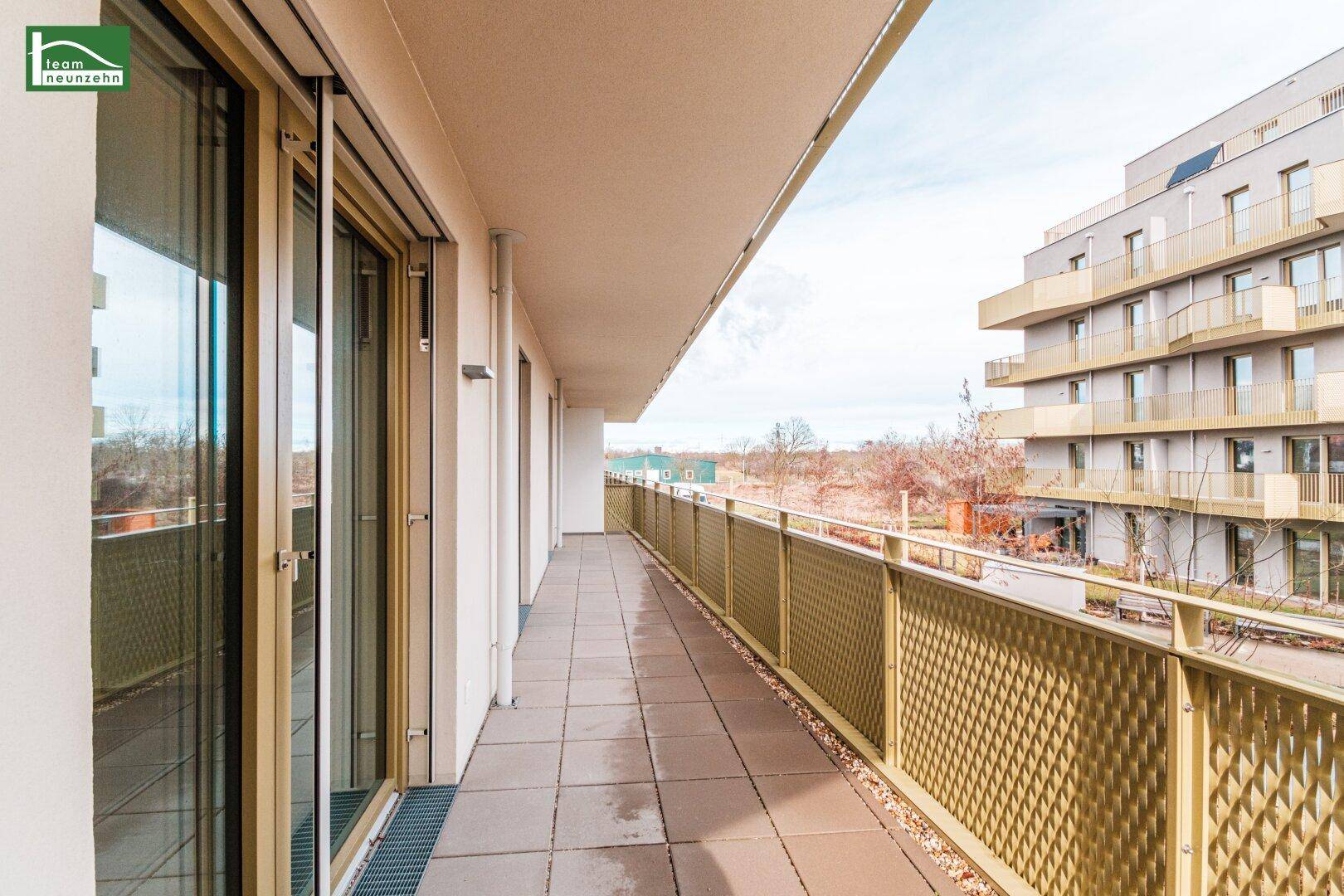 Langer Balkon mit mehreren Zugängen und Blick auf die Umgebung.