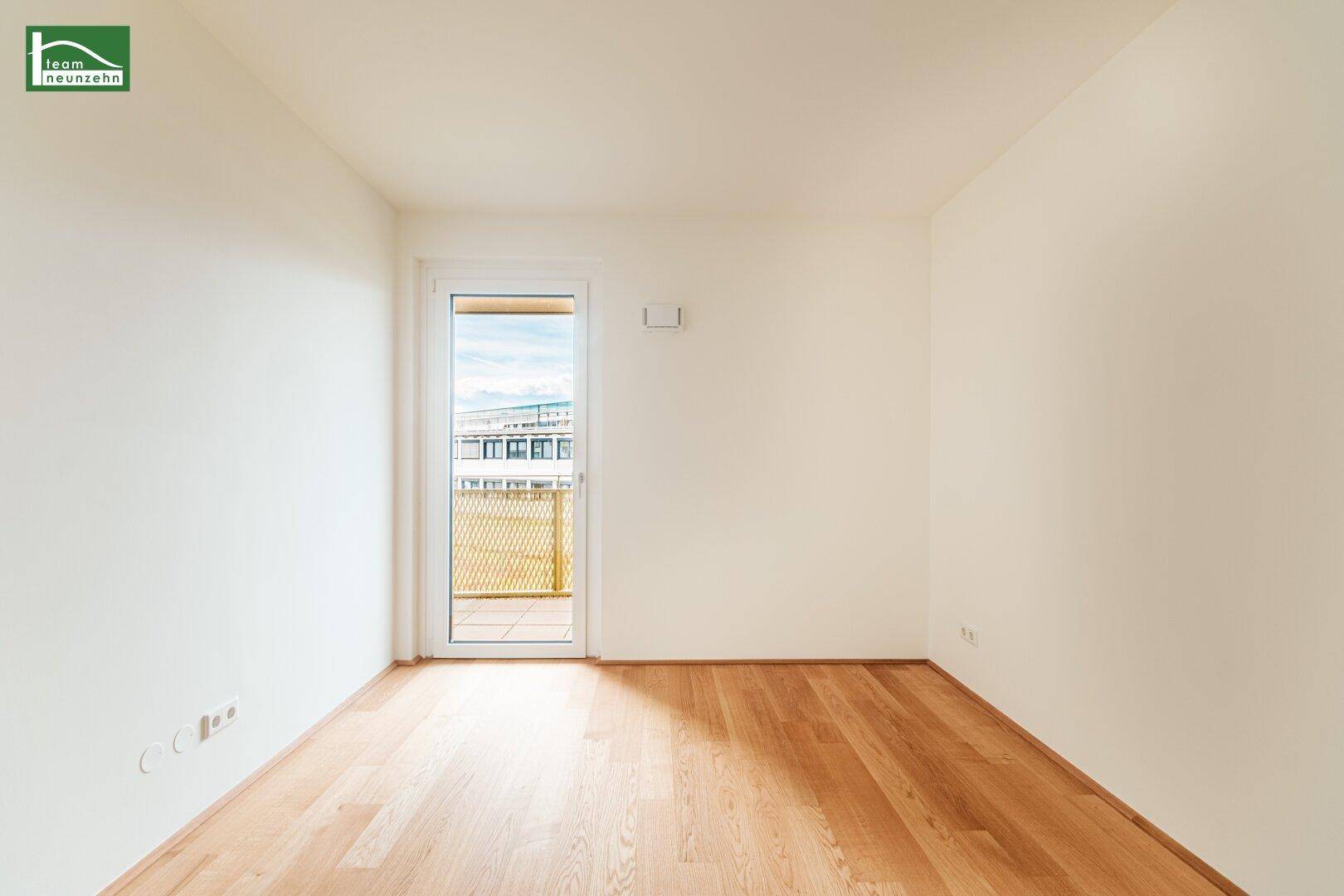 Lichtdurchflutetes Zimmer mit Holzboden und Balkontür, bietet eine angenehme Wohnatmosphäre.