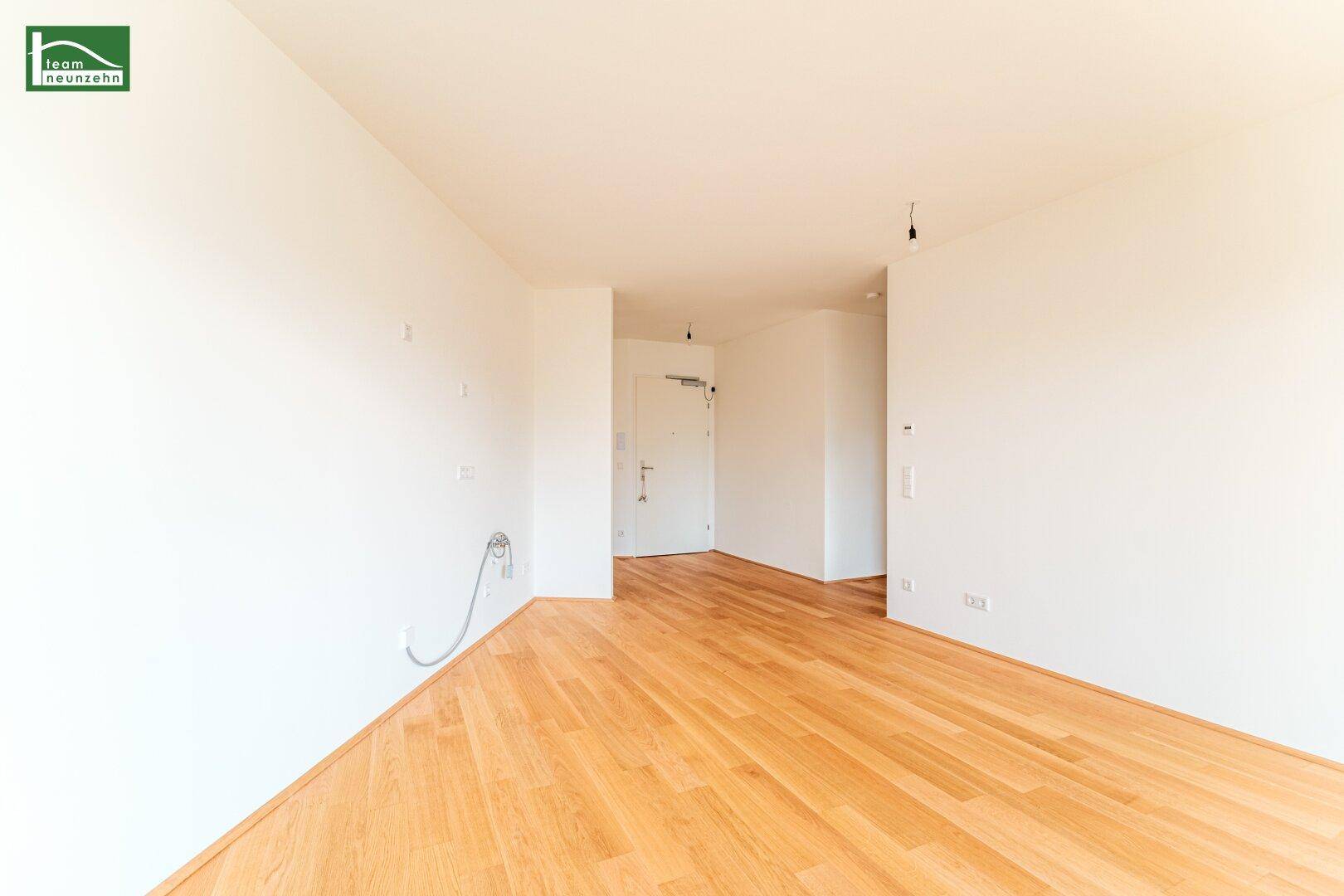 Heller Eingangsbereich mit Parkettboden und Zugang zur Wohnungstür, modern gestaltet.