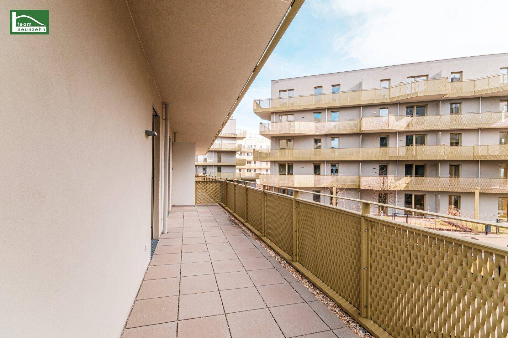 Geräumiger Balkon mit Fliesenboden und Blick auf die moderne Wohnanlage.
