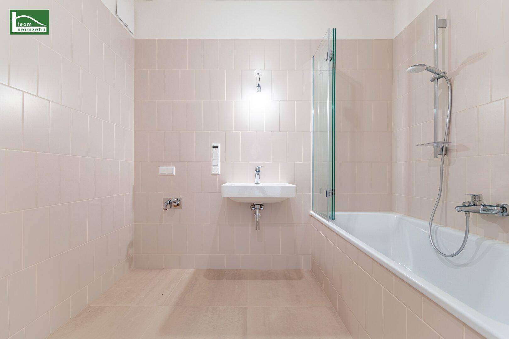 Modernes Badezimmer mit Badewanne, Duschabtrennung und beigefarbenen Fliesen.