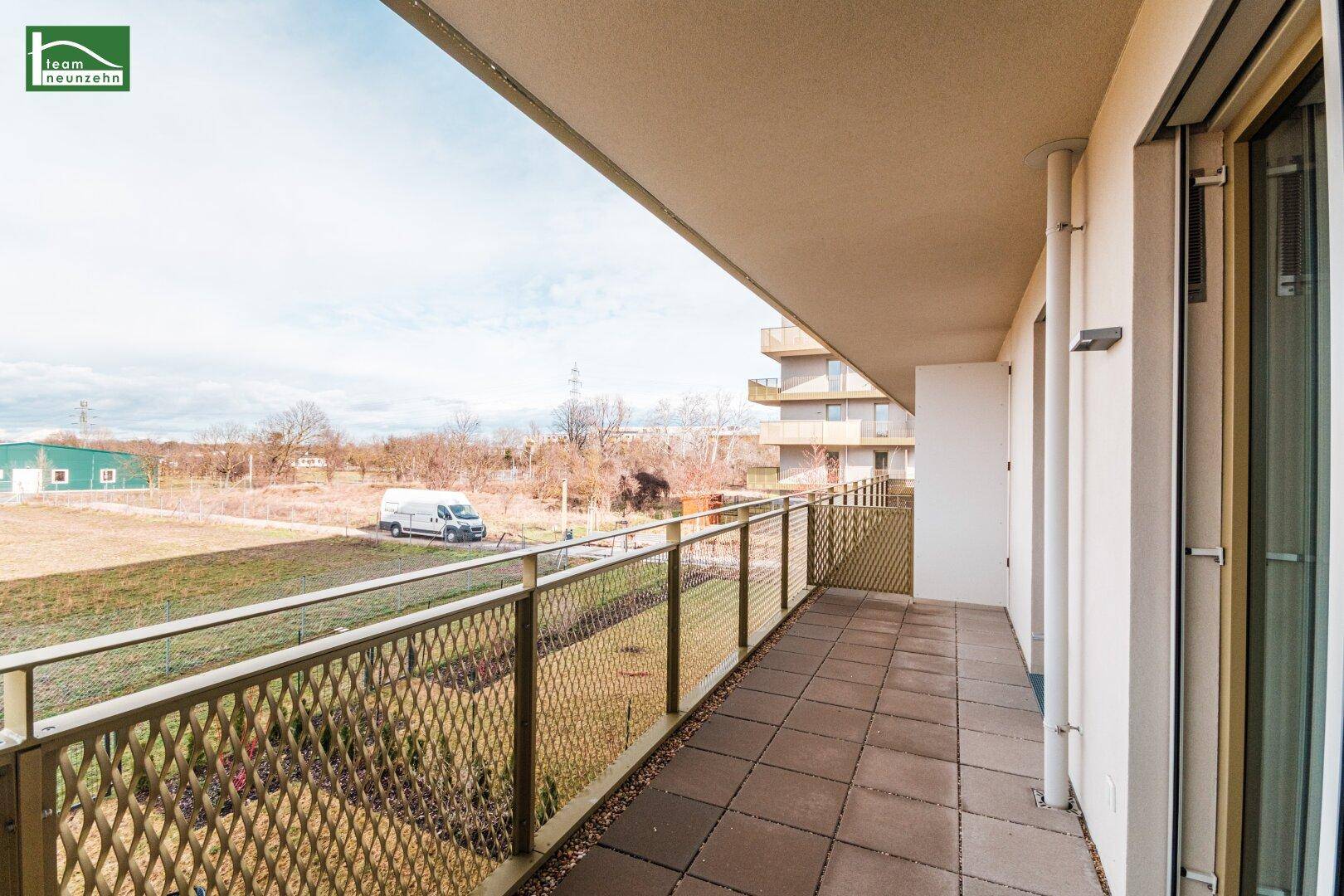 Langer Balkon mit Fliesenboden und Metallgeländer, bietet einen weiten Blick ins Grüne.