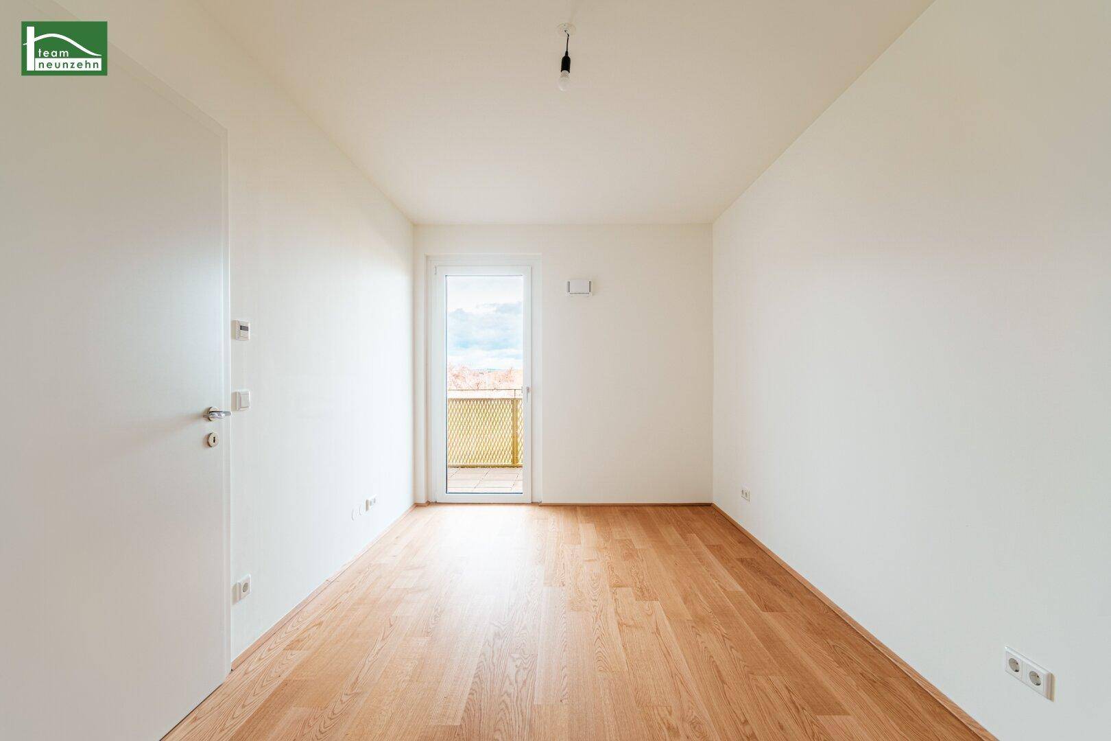 Helles Schlafzimmer mit Holzboden und direktem Zugang zu einem kleinen Balkon.