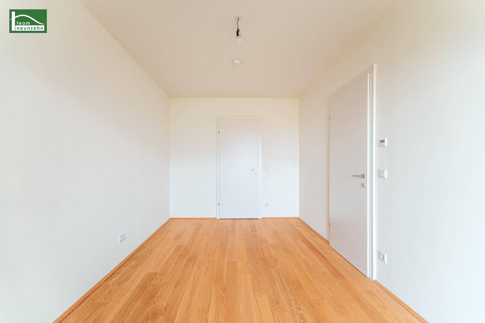 Leeres Zimmer mit hellem Holzboden und weißen Wänden, bereit für individuelle Einrichtung.