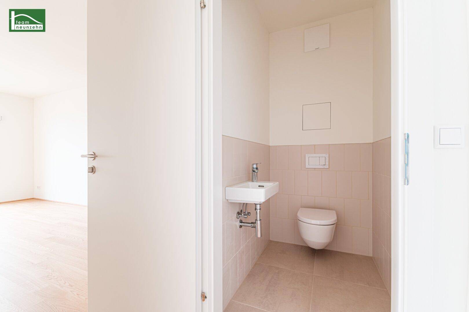 Funktionelles Gäste-WC mit wandhängender Toilette, kleinem Waschbecken und hellen Fliesen.