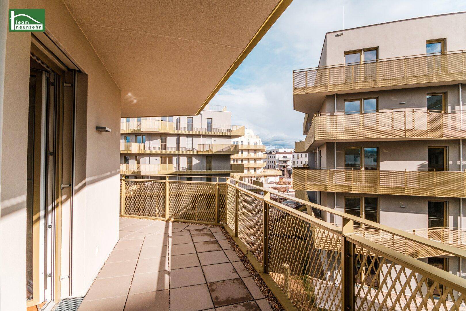 Geräumiger Balkon mit Fliesenboden und Blick auf die umliegenden modernen Wohngebäude.