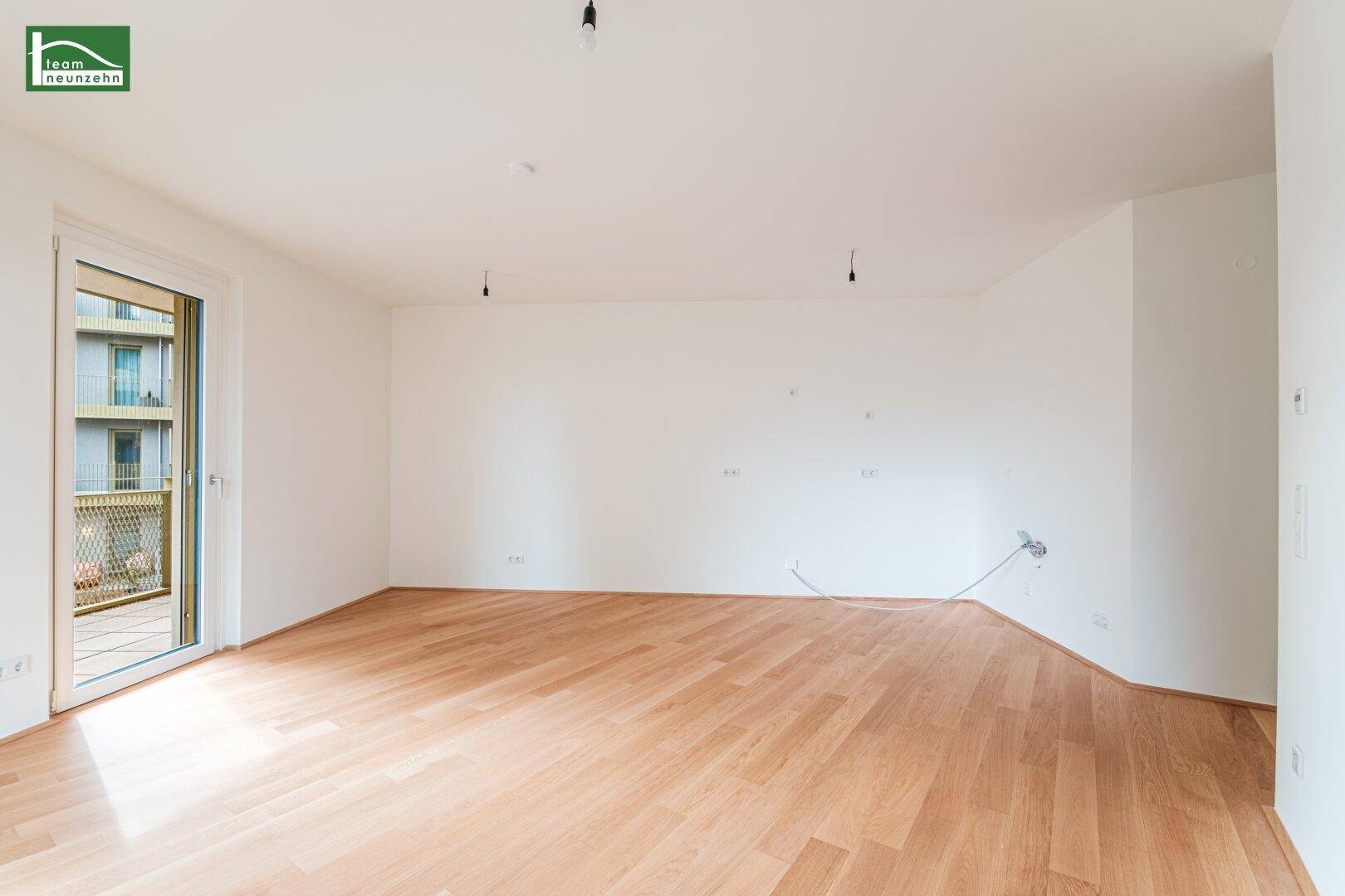 Geräumiges, unmöbliertes Zimmer mit hellem Parkett und direktem Zugang zum Außenbereich.