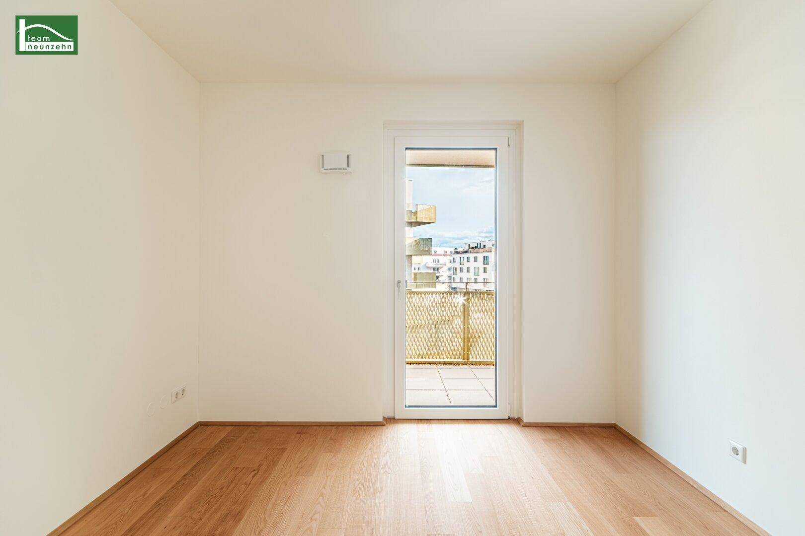 Ruhiges Schlafzimmer mit hellem Parkettboden und Balkontür, bereit für die individuelle Gestaltung.