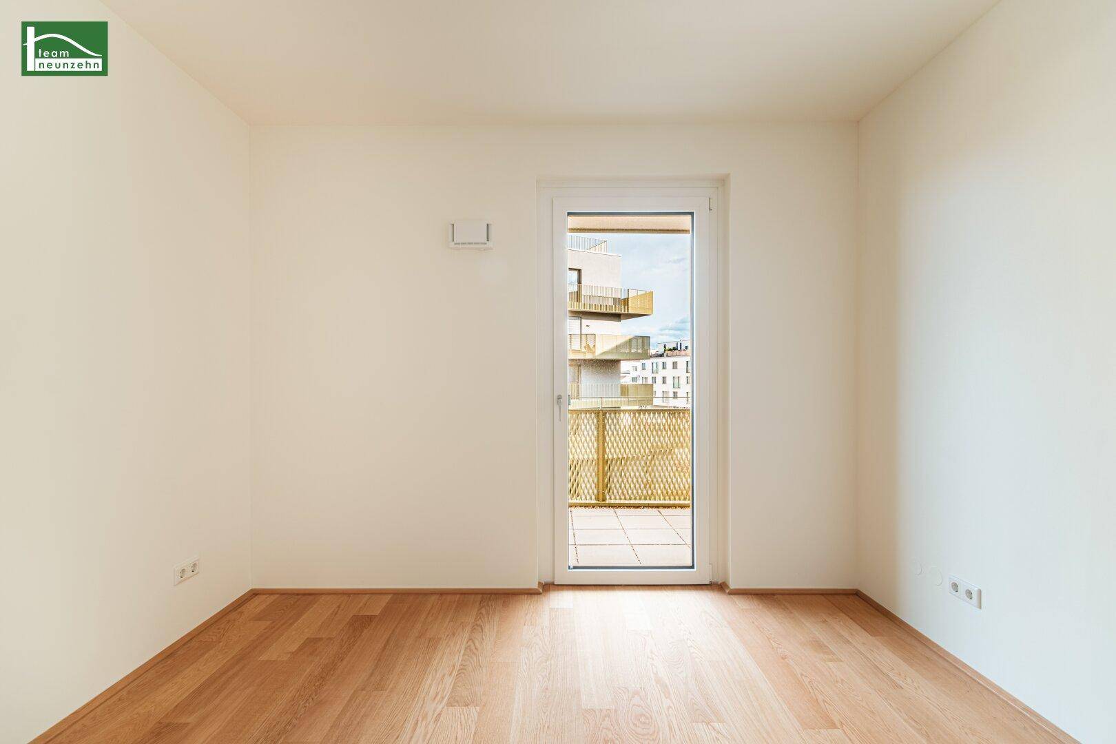 Freundliches Zimmer mit Parkett und Balkonzugang, bietet viel Tageslicht und frische Luft.