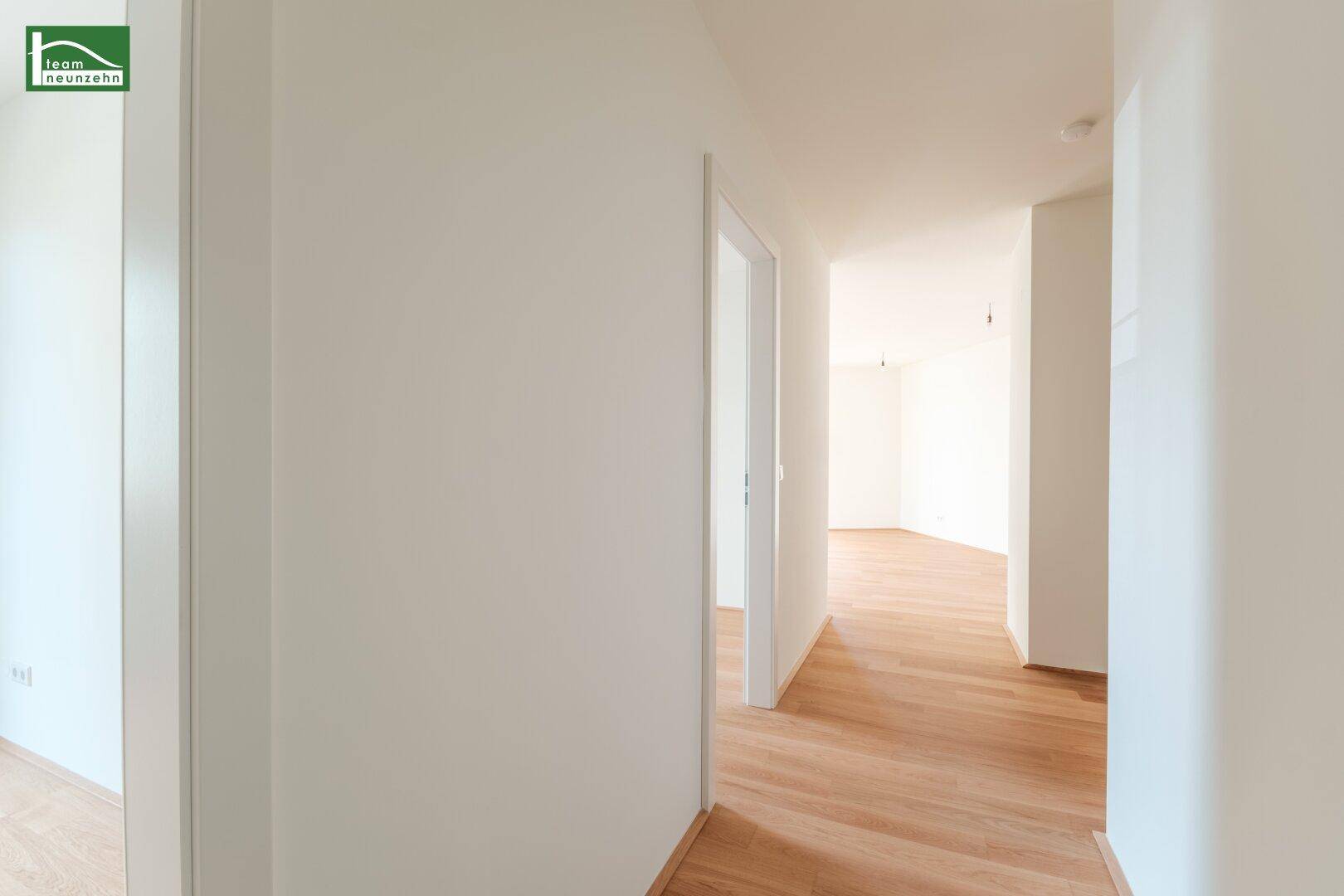 Heller Flur mit Parkettboden, der zu verschiedenen Räumen der Wohnung führt.