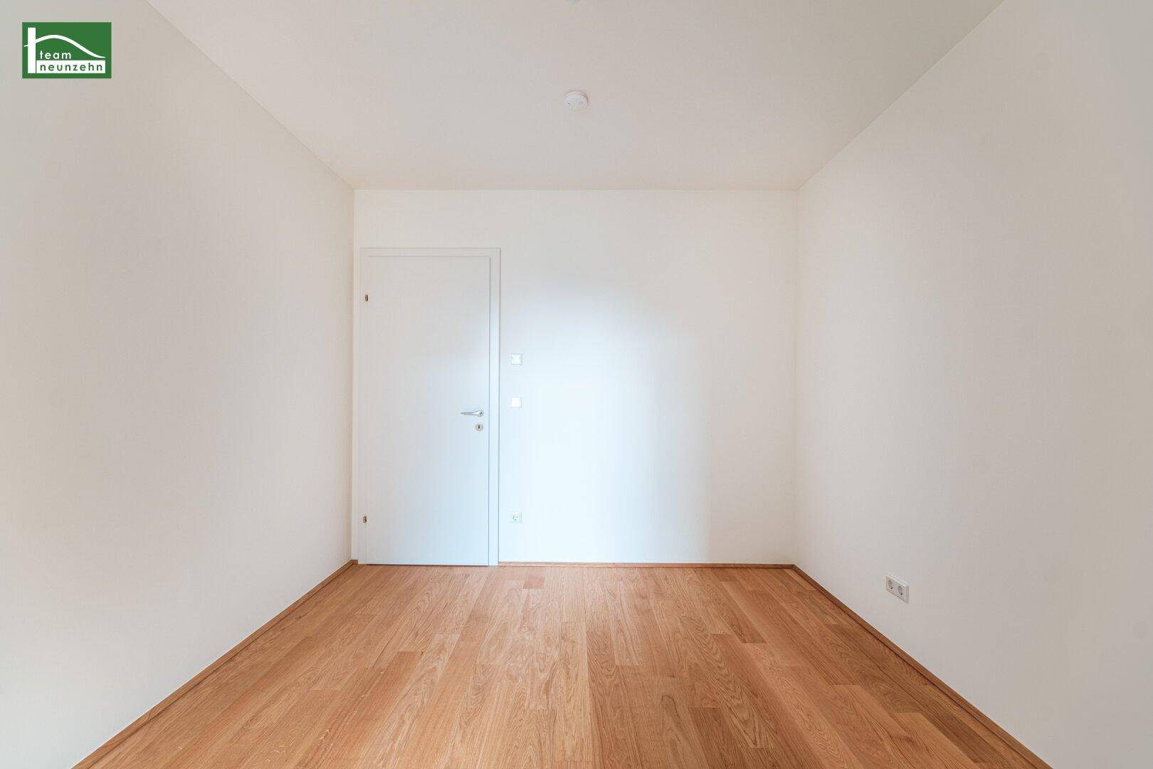 Leeres Zimmer mit Holzboden und weiß gestrichenen Wänden, vielseitig nutzbar.