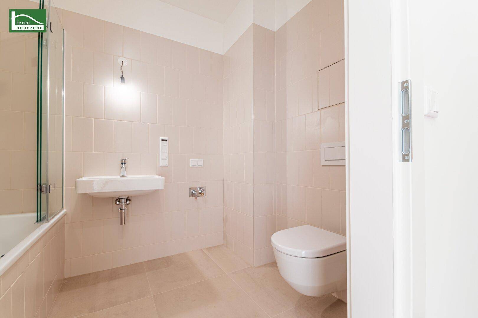 Funktionales Badezimmer mit beigefarbenen Fliesen, wandhängendem WC und modernem Waschbecken.