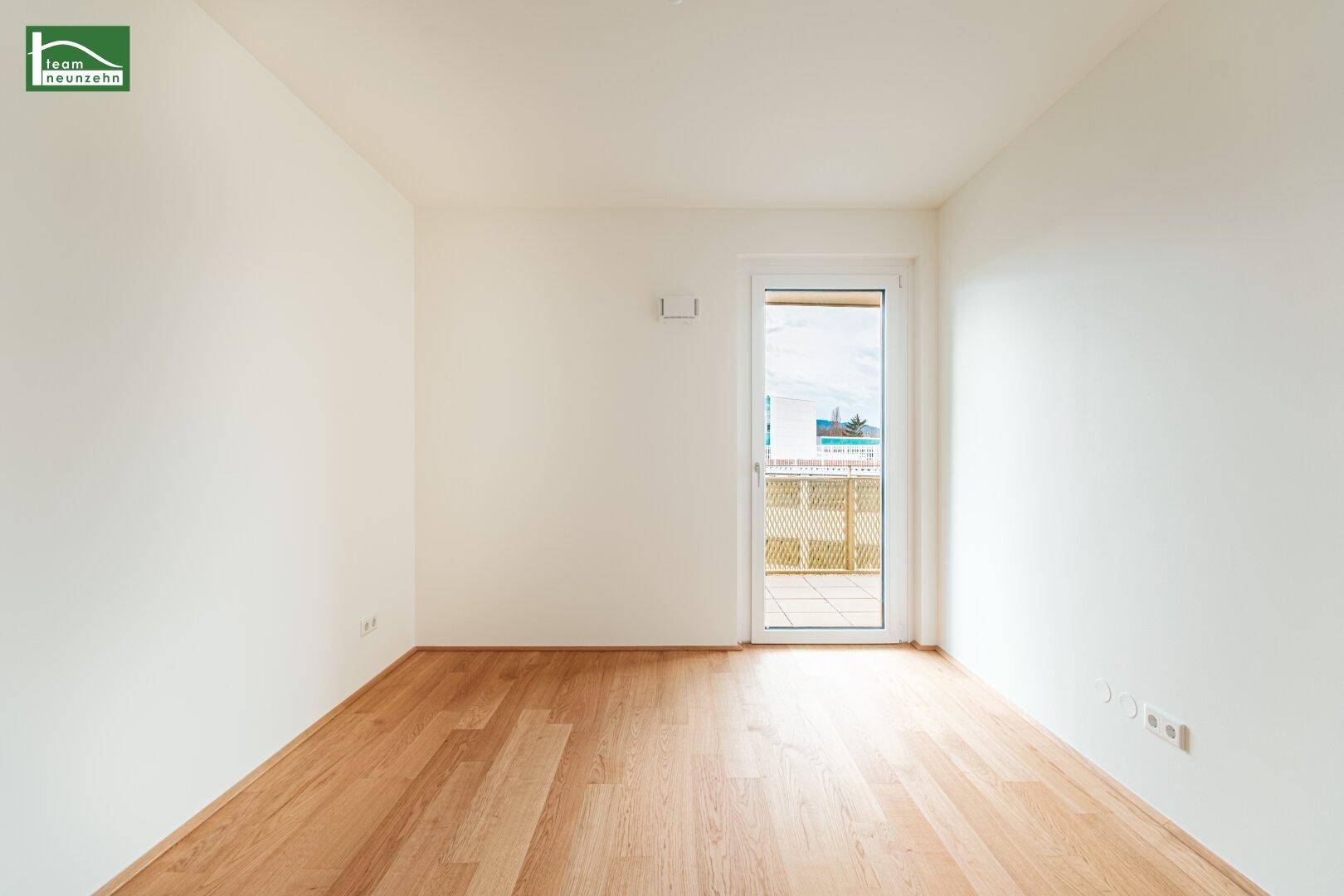 Leeres Zimmer mit Parkettboden und Zugang zu einem Außenbereich, ideal als Schlafzimmer.