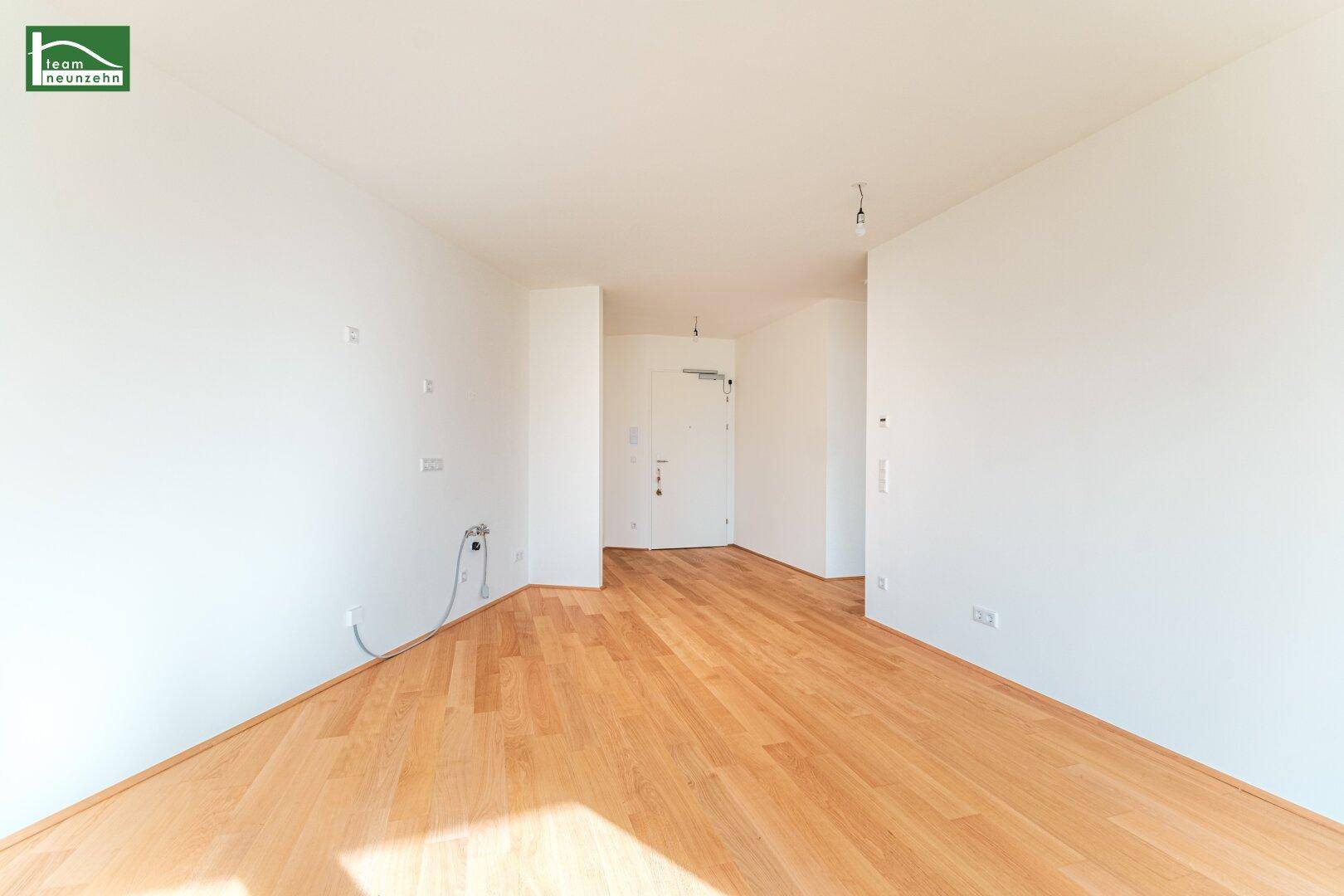 Heller Eingangsbereich mit Holzboden und weiß gestrichenen Wänden, bereit für die Einrichtung.