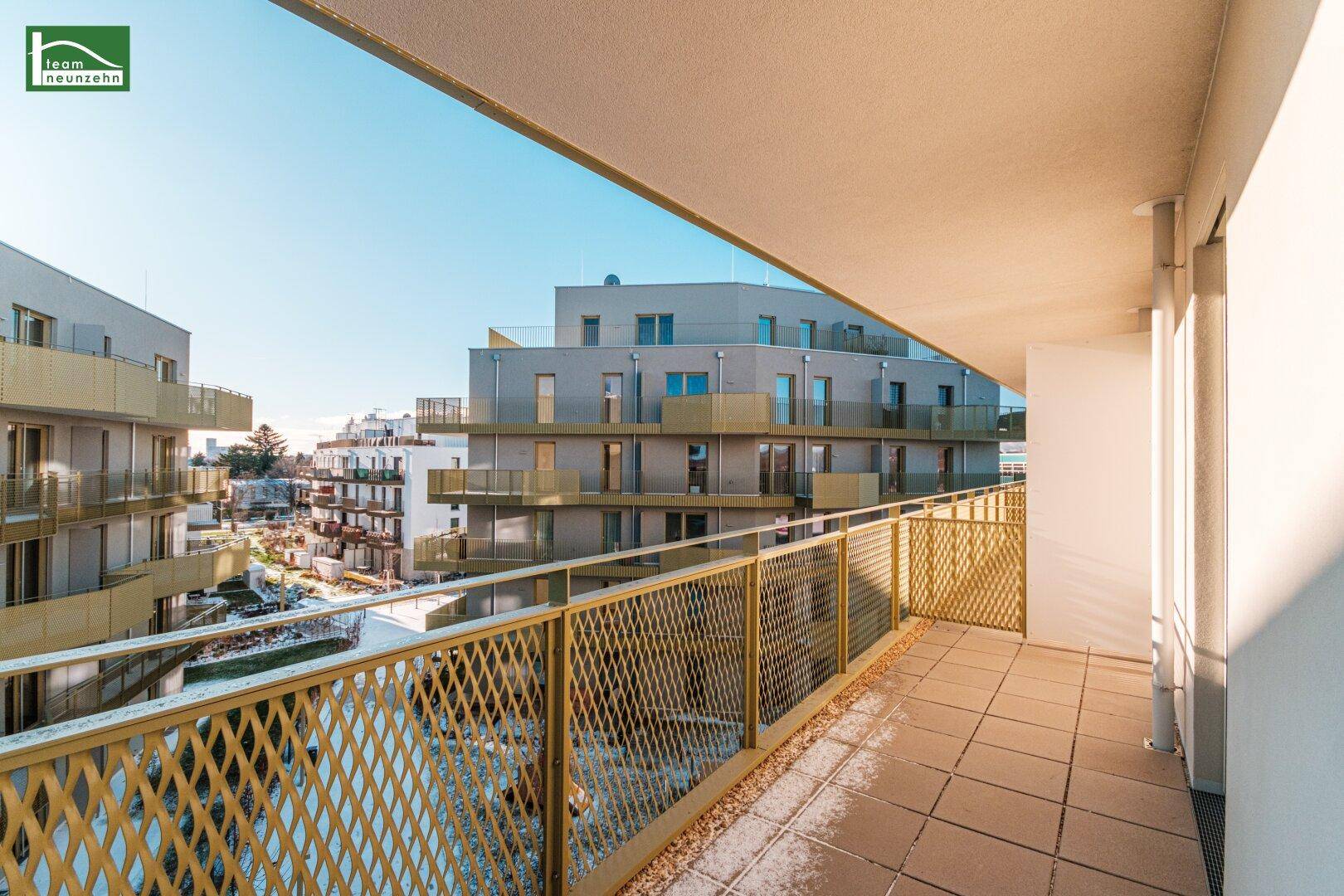 Geräumiger Balkon mit modernen goldenen Geländern und Blick auf die umliegenden Gebäude.