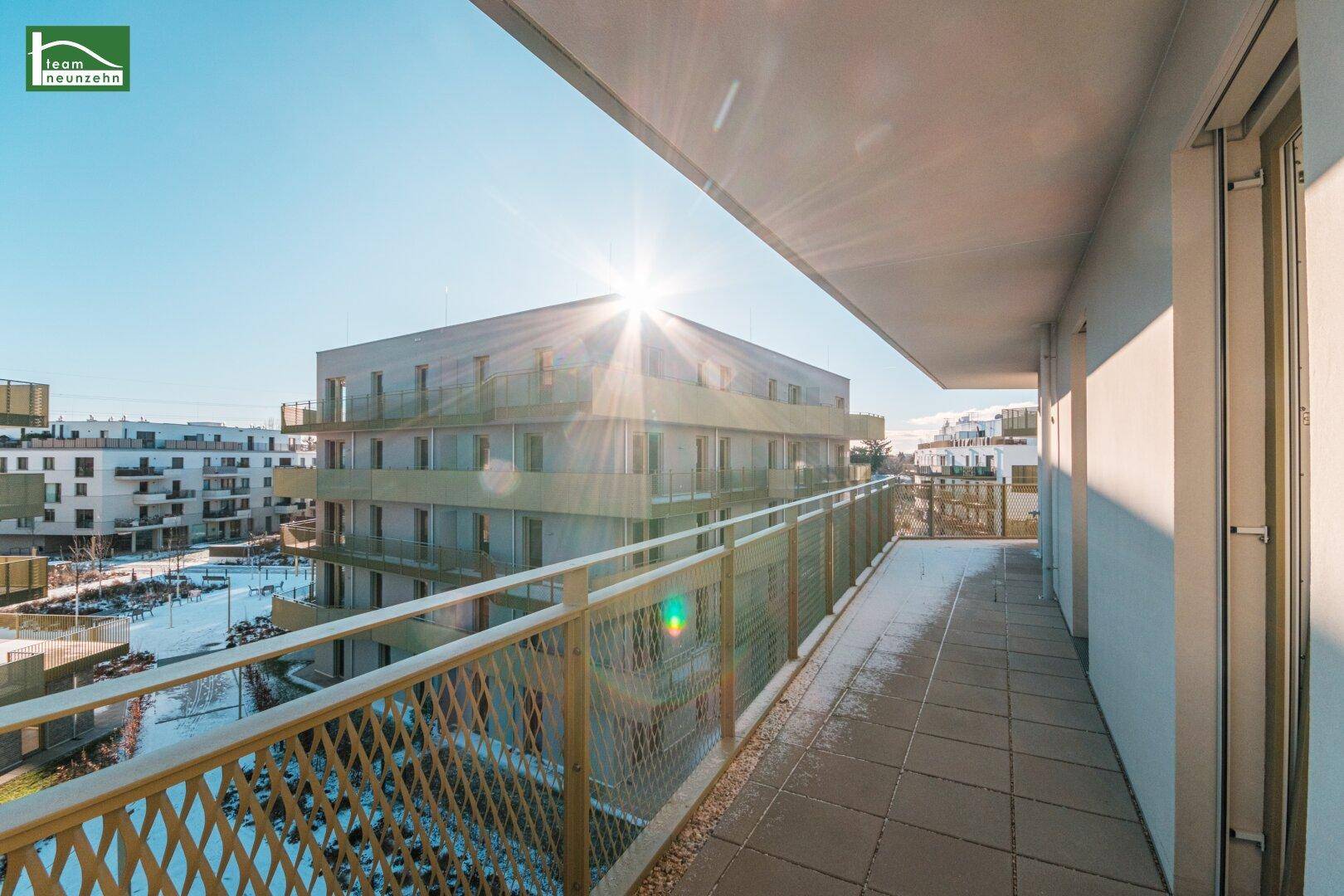 Sonniger Balkon mit Fliesenboden und weitem Blick über die moderne Wohnanlage.