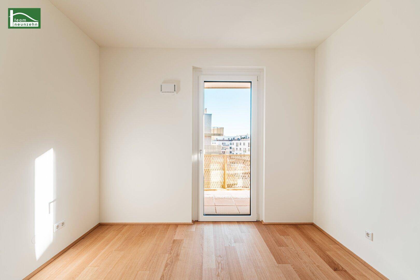 Schlafzimmer mit Parkettboden und Zugang zu einem kleinen Balkon oder einer Loggia.