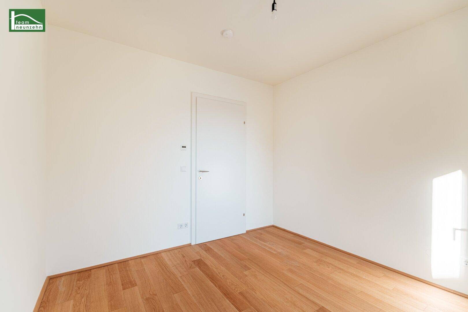 Helles Schlafzimmer mit Parkettboden und weißer Tür, bereit zur individuellen Gestaltung.