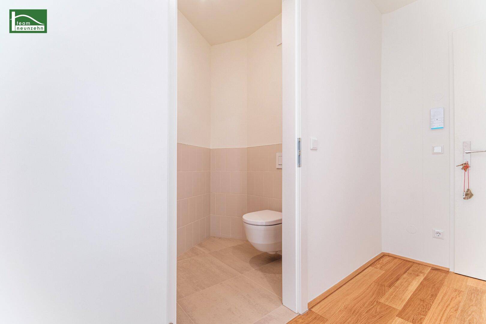 Modernes Gäste-WC mit wandhängender Toilette und hellen Fliesen, sauber und minimalistisch.