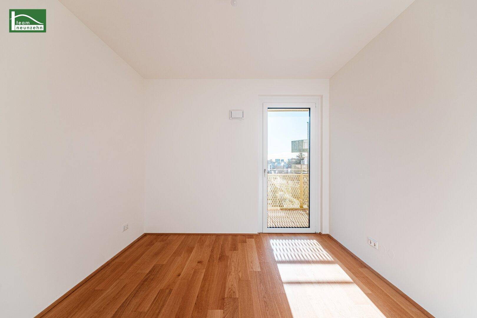 Schlafzimmer mit Parkettboden und Zugang zu einem kleinen Balkon.