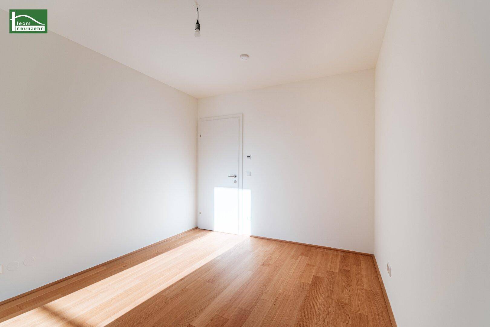 Helles Zimmer mit Parkettboden und weiß gestrichenen Wänden.