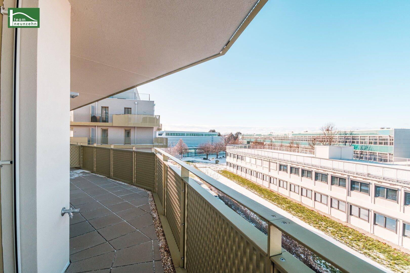 Geräumiger Balkon mit Fliesenboden und Metallgeländer, bietet Ausblick auf die umliegenden Gebäude.