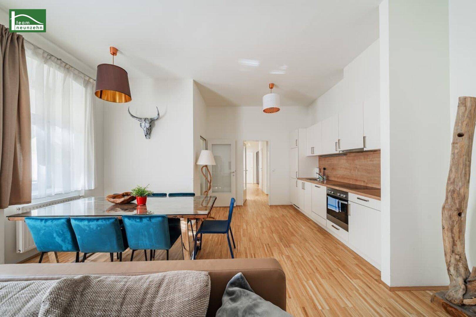 Heller offener Wohn- und Essbereich mit integrierter moderner Küche, Parkettboden und hohen Decken.