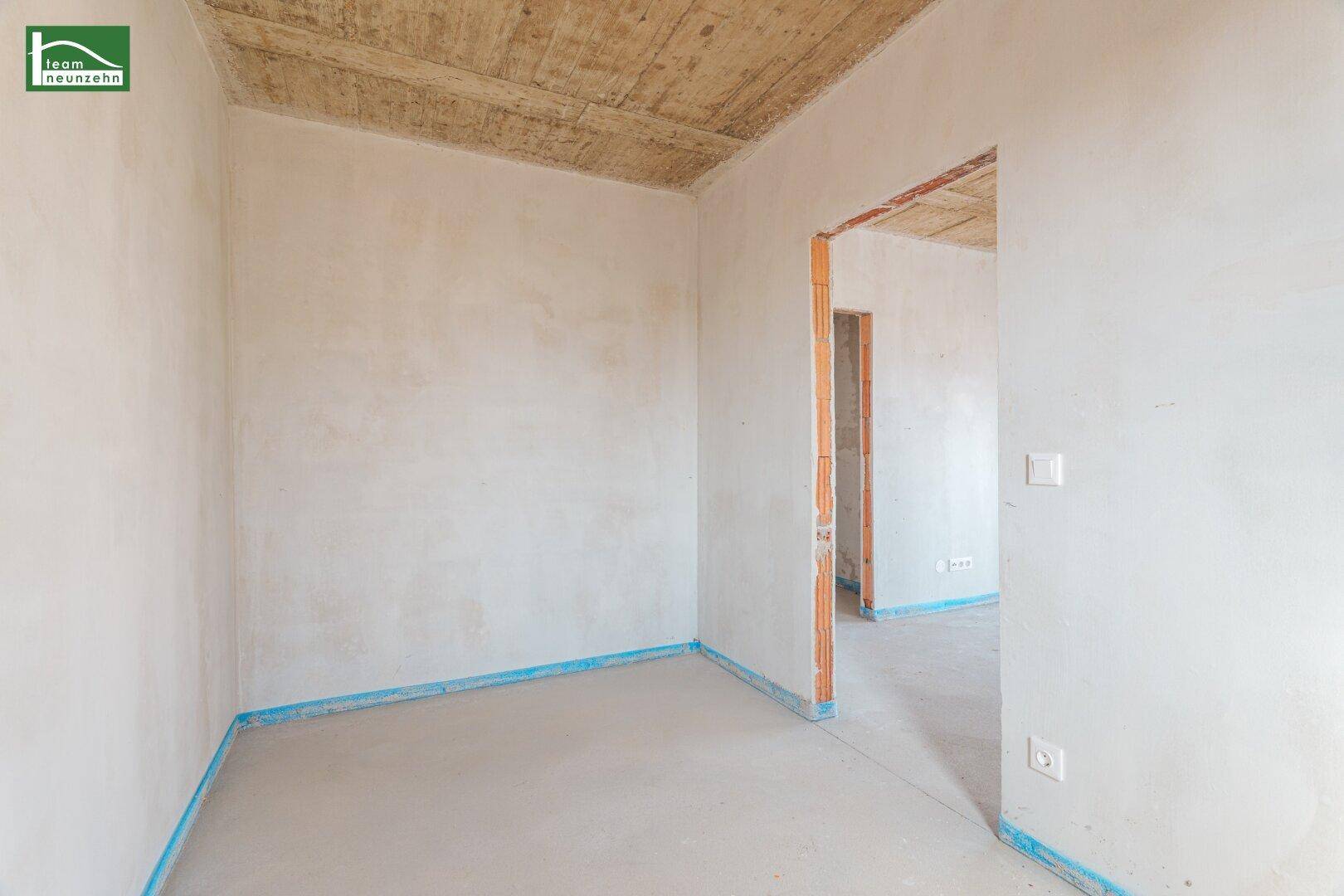 Unfertiger Innenraum mit Betonboden und unverputzten Wänden, bereit für den Ausbau.