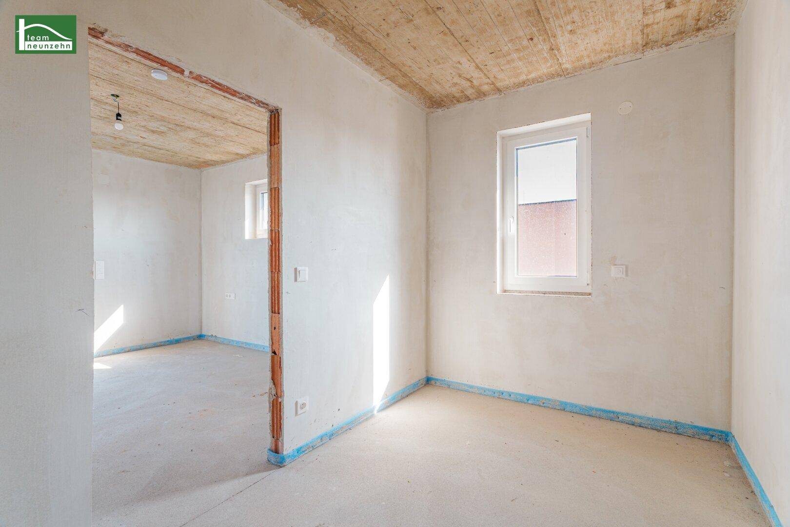 Unfertiger Innenraum mit Betonboden und Fenster, bereit für den weiteren Ausbau.