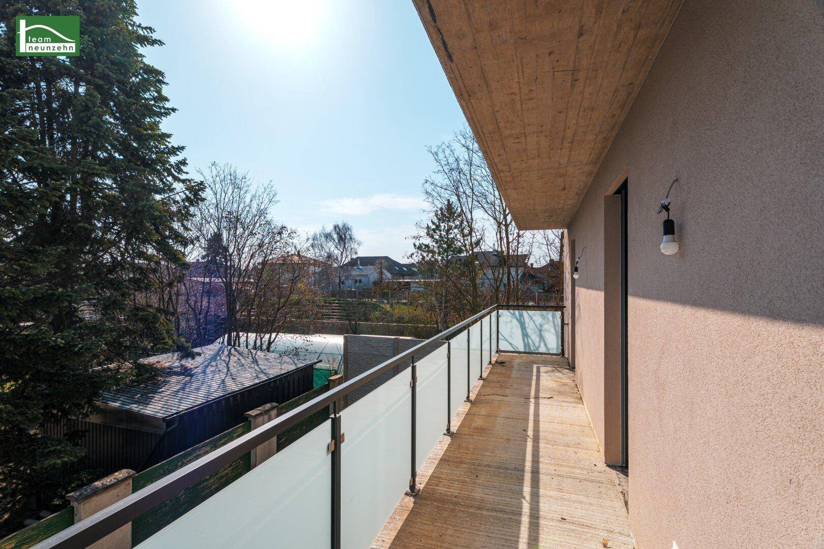 Sonniger Balkon mit modernem Glasgeländer und weitem Blick über die Umgebung.