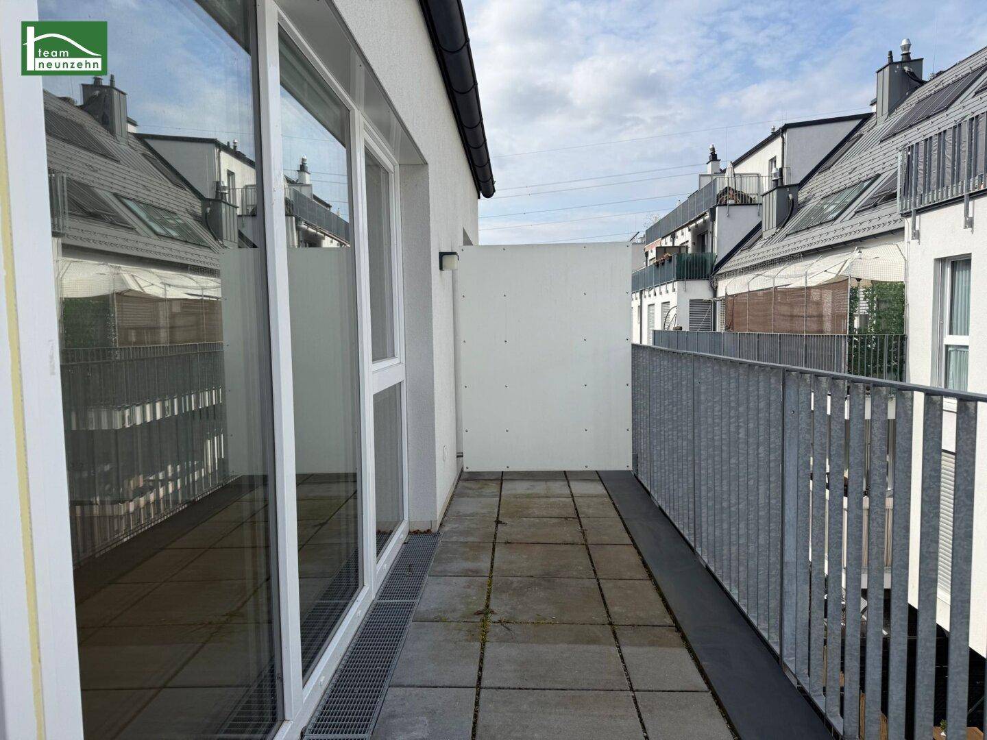 Geräumiger Balkon mit Fliesenboden und Blick auf die umliegenden Gebäude.