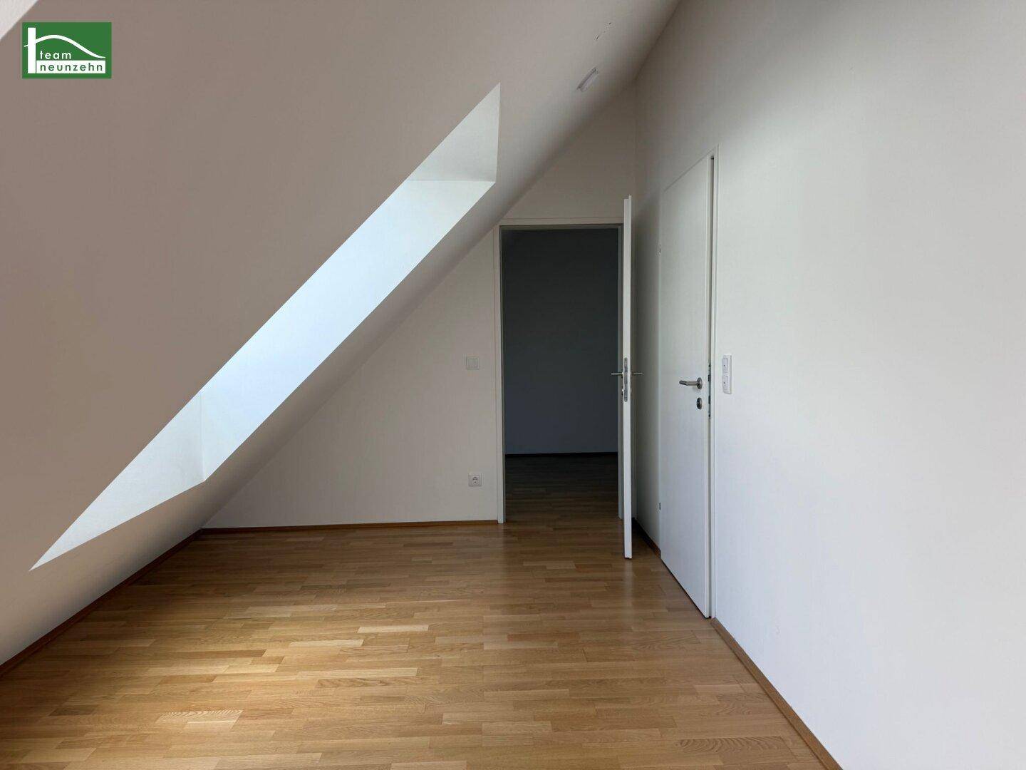 Leerer Raum im Dachgeschoss mit schräger Wand und viel natürlichem Licht.