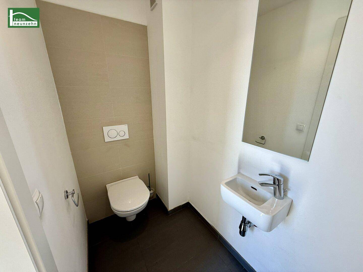 Kleines Gäste-WC mit wandhängender Toilette, Handwaschbecken und einem Spiegel.