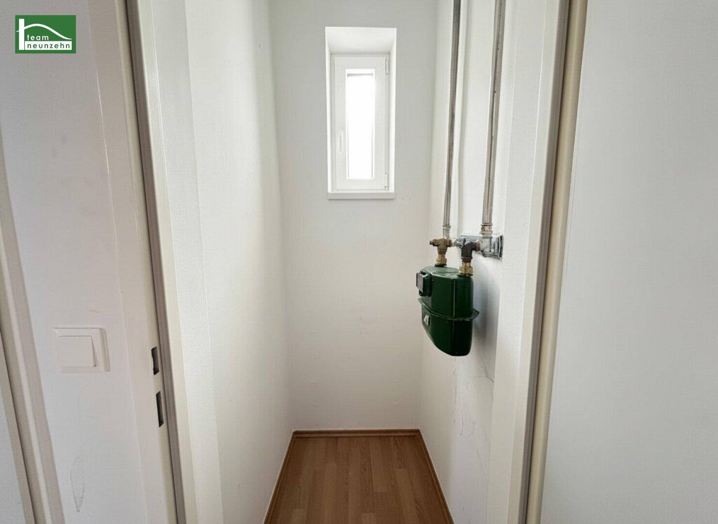 Kleiner Abstellraum mit Fenster und sichtbaren Gasleitungen und Zähler.