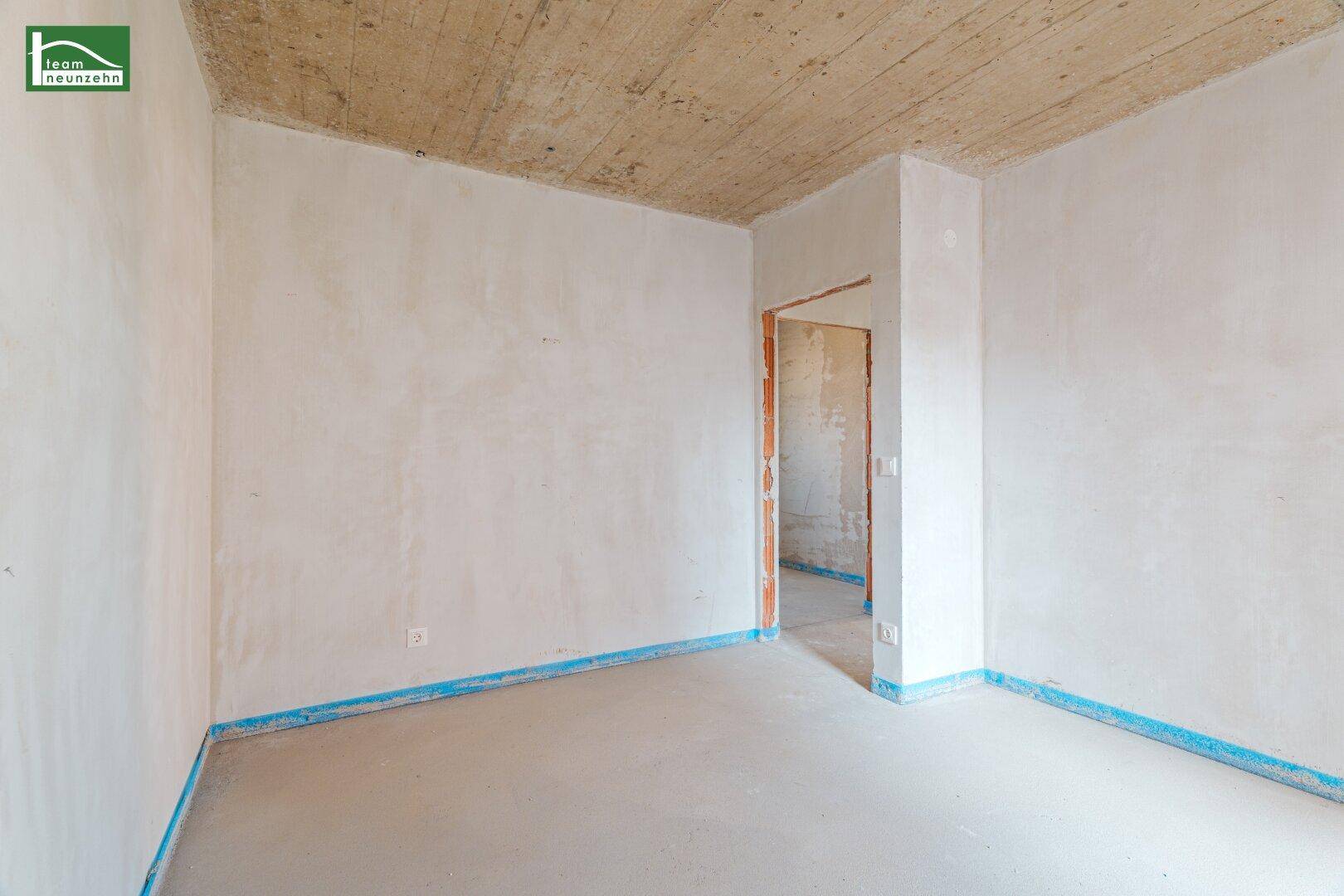 Unfertiger Raum mit Türrahmen und Rohbetondecke, bereit für den weiteren Ausbau.
